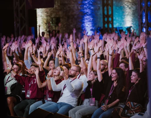 A group of people cheering and raising their hands at an indoor event.